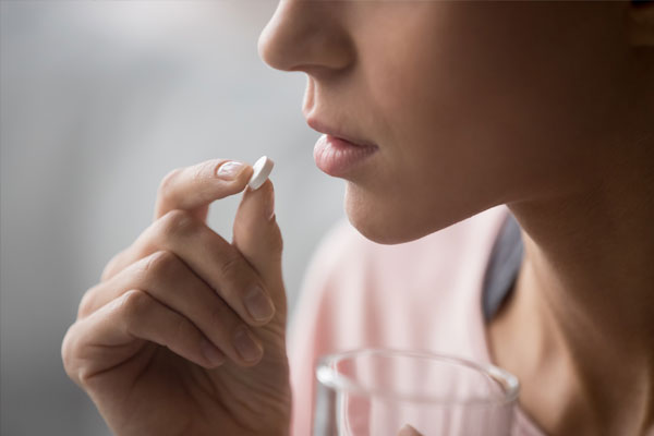 Woman holding abortion pill with a glass of water.